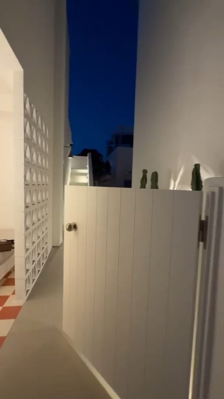 Walking through the white courtyard gate of the house at dusk