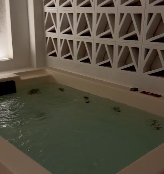 The filled outdoor jacuzzi beside the lattice screen
