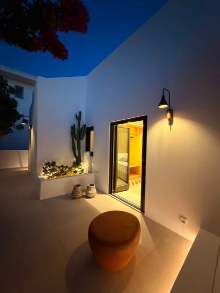 The lit doorway of the house at dusk, bougainvillea against a deep blue sky