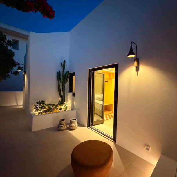 The lit doorway of the house at dusk, bougainvillea against a deep blue sky