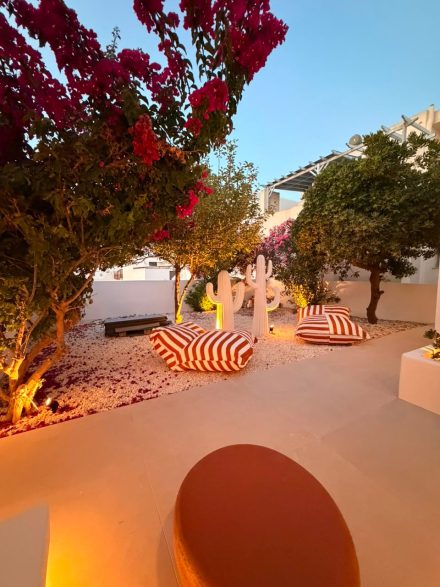 Whitewashed courtyard with striped sunbeds under flowering bougainvillea