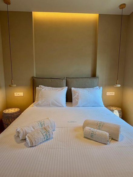 A second double bed with folded towels and warm evening lighting