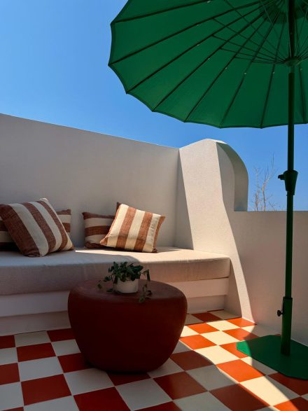 Built-in terrace seating with striped cushions under a green parasol